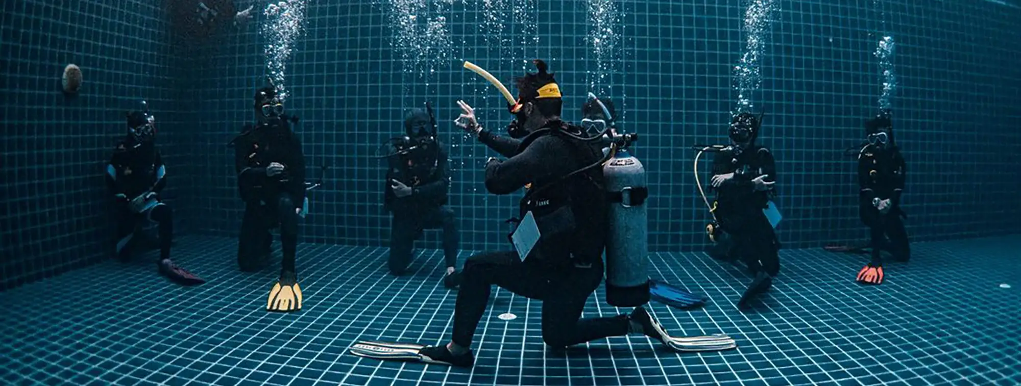 PADI Instructor Course training session in a pool, with an instructor demonstrating skills to a group of candidates.